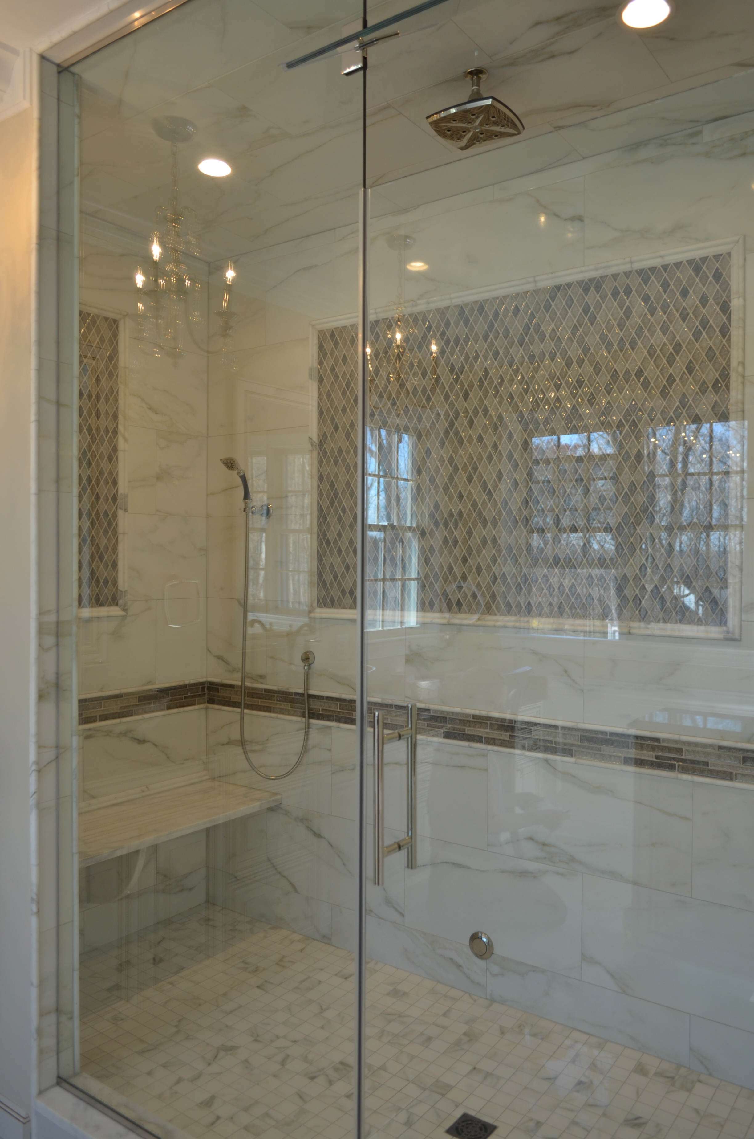 Luxury bathroom remodel featuring a marble-tiled walk-in shower with glass enclosure, rainfall showerhead, built-in bench, and diamond-pattern accent tile for an elegant spa-inspired design.